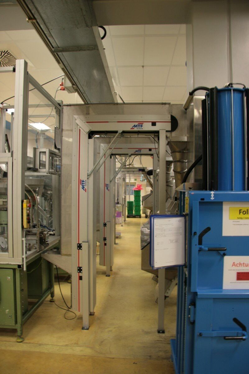 Vertical conveyor belt with cover and pipe system connection for the vertical transport of medical technology articles